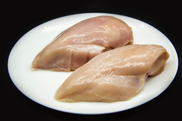 Fresh raw chicken fillet on a white plate against a background. Chicken fillet without non-GMO. Raw chicken breasts on the plate
