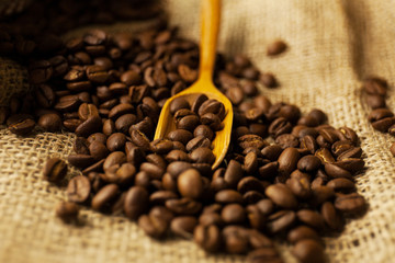 scattered Coffee beans spilling from a burlap bag and a scoop