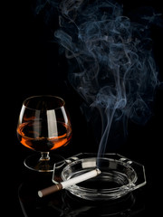 Smoking cigarette and cognac in glass container