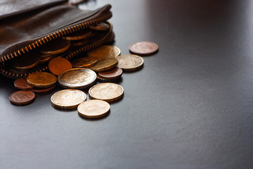 Leather wallet with some euro coins on black background, money saving concept. Place for text