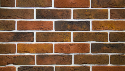The background is made of artificial stone of black and brown color and has a rectangular shape in the form of a wall made of burnt bricks. Backgrounds, textures, and design.