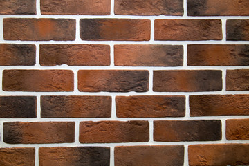 The background is made of artificial stone of black and brown color and has a rectangular shape in the form of a wall made of burnt bricks. Backgrounds, textures, and design.