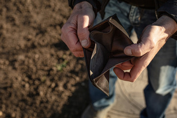 An elderly man shows an empty wallet.