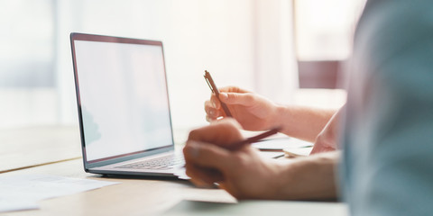 Closeup of man hands using laptop and holding pan