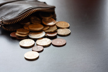 Leather wallet with some euro coins on black background, money saving concept. Place for text