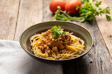 Spaghetti bolognese with parmesan cheese on wooden background
