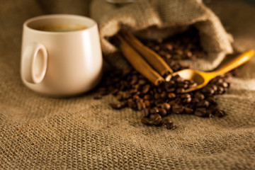 Coffee cup with cinnamon sticks and coffee bag on wooden table