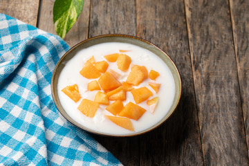 Cantaloupe melon with yogurt in bowl on wooden background