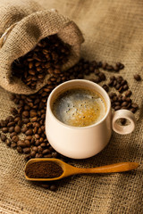 Coffee cup with cinnamon sticks and coffee bag on wooden table