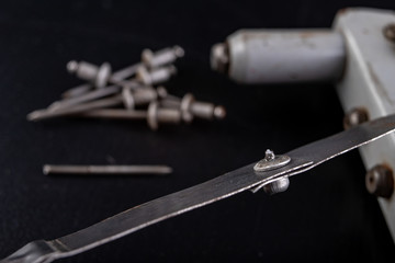 Riveting two pieces of metal sheet. Connecting steel with rivets.