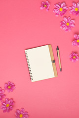 Paper note with flowers on pink background. Top view.