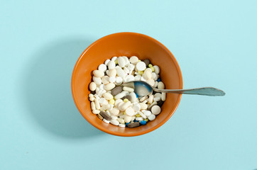 Medication with a spoon. Plate with medicines on a blue background.