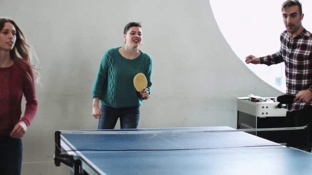 adult group playing table tennis in office