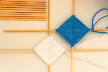 Weaving mandalas from colored yarn on wooden sticks.