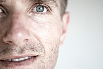 Detail close-up of mid-adult Caucasian man with wrinkles and stubble next to blank copy space