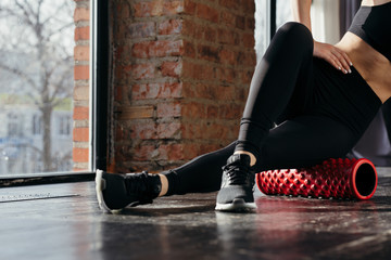 The exercises at the hip. The girl crossed her legs and massage the thigh sports a red cylinder.