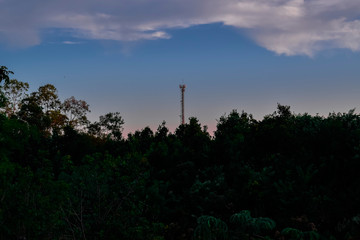 Obraz premium Horizonte com silhueta de floresta e torre de comunicação. 