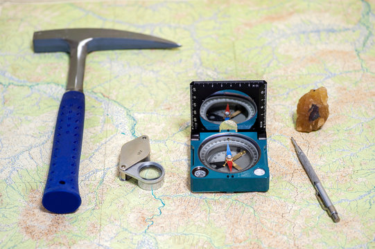 The Tools Of The Geologist Laid Out On A Topographic Map. Background