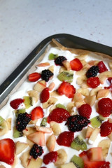 Making yogurt bark. Pieces of fruit in a yogurt before freezing. Selective focus.