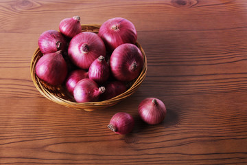 some onions in a basket on wood texture background 