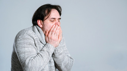 An adult brutal man in knitted sweater fell ill with pneumonia. annoying cough.