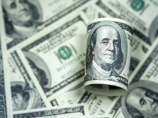 Roll of hundred dollar bill on dollar