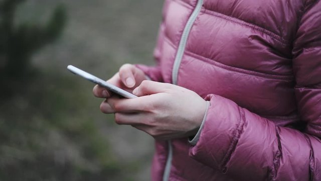 Hands in pink jaket holding while mobile phone while texting very fast