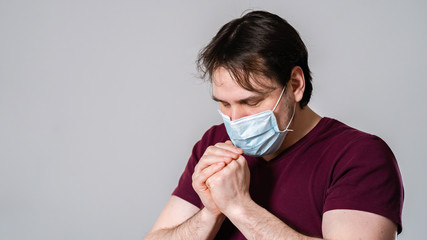 young man in mask, praying for salvation and protection from dangerous virus.