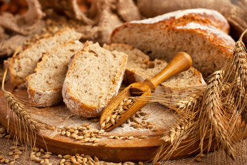 Rustic loaf of homemade bread sliced on  wooden  board