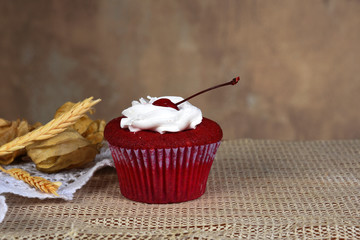 red fruit cake cupcake with whipped cream and a cherry on top punch the table on blurred background with space for text