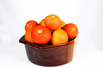 various juicy and tasty tomatoes in a clay pot isolated on white background