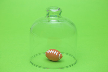 American football ball under glass cover isolation covid-19 abstract.