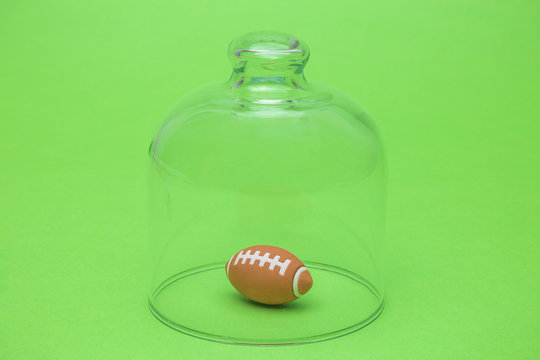 American Football Ball Under Glass Cover Isolation Covid-19 Abstract.