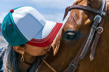 Detalhe de tratadora quase beijando o seu cavalo de cor alazão, da raça quarto de milha.