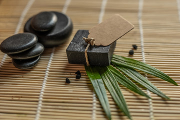 charcoal coal carbon black soap bar on a raw wood bamboo background lava stone spa skin care hygiene concept 