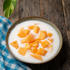 Cantaloupe melon with yogurt in bowl on wooden background