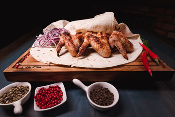 Appetizing fried chicken wings on a wooden tray. Studio photography of food in the cooking industry, dark background