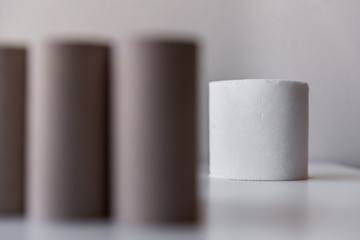 One whole roll of toilet paper looking at the blurry empty cushions in the foreground on white table