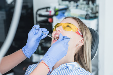 A dentist examines a patient, close-up of a patient with an open mouth next to which dental objects. The concept of health care and treatment in medical facilities