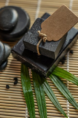 bar block of black carbon charcoal coal soap on a bamboo background with lava stones spa concept