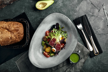 Nicoise salad with tuna on a gray plate, on a serving table. A beautiful dish from the chef, food...