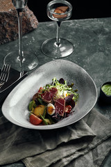 Nicoise salad with tuna on a gray plate, on a serving table. A beautiful dish from the chef, food photo, gray background, copy space, traditional French cuisine.
