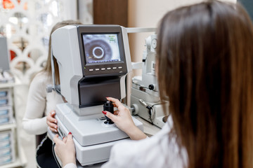 Close up photo, female doctor testing person for her eyes with special optical apparatus in modern...