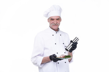 Cook with happy face, elderly chef male holds steak meat and pepper. Man with beard isolated on white background