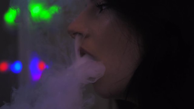 Girl smoking vape, inhaling an e-cigarette, vape smoke, slow motion close up