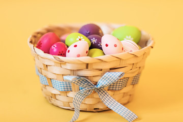 Colorful Easter eggs in a basket on an isolated yellow background