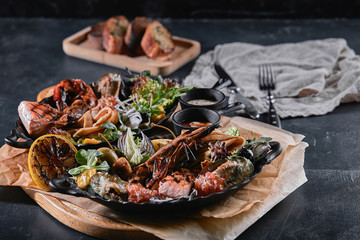 Assorted seafood on plates. Beautiful composition on a served seafood table, squid, shrimp, salmon steak and octopus. Food photo, low key, traditional Italian cuisine. Top view, save the space