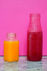 Glass bottles filled with colorful homemade beet smoothies