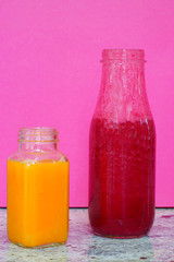 Glass bottles filled with colorful homemade beet smoothies