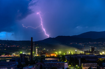 Lightning over the city at the summer storm. Dramatic, breathtaking atmospheric natural phenomenon.Beautiful dark storm sky. Clouds and thunder lightnings.Bright lightning in the black sky